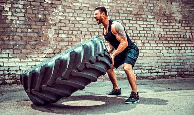 bearded man training with a car tire