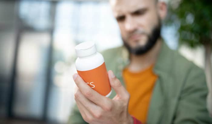 bearded man looking at supplement bottle