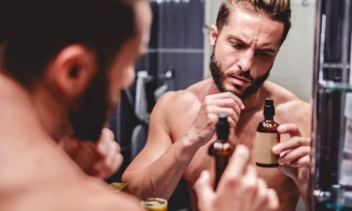 man looking at beard oil ingredient label