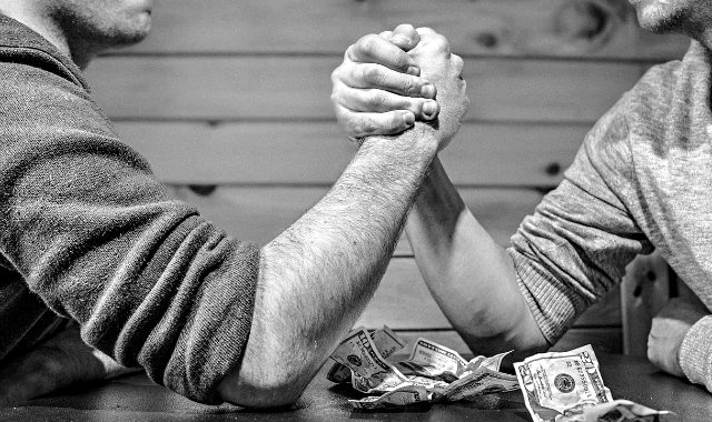 two man competing in an arm wrestling with money as wager