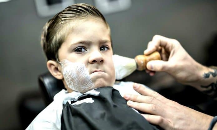 little kid getting a shave at a barber shop