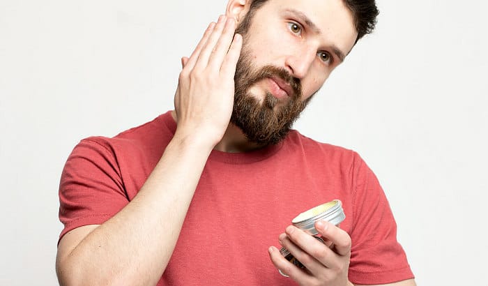 man applying beard butter to his face