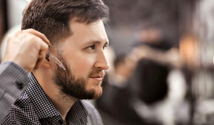 man applying beard oil to cheeks