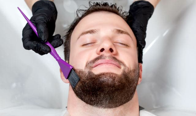 man getting his short beard dyed at salon