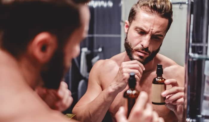 man looking at beard oil bottle