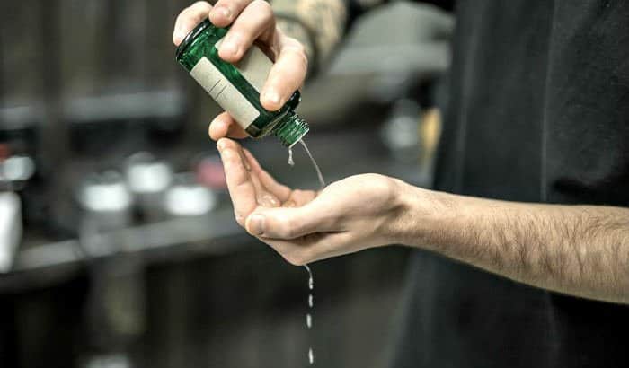 man pouring beard growth oil