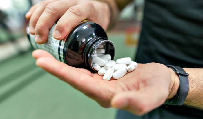 man pouring fitness supplements to his palm