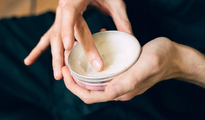 man scooping out beard butter from a tin