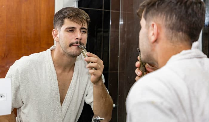 man shaping his mustache in front of a mirror