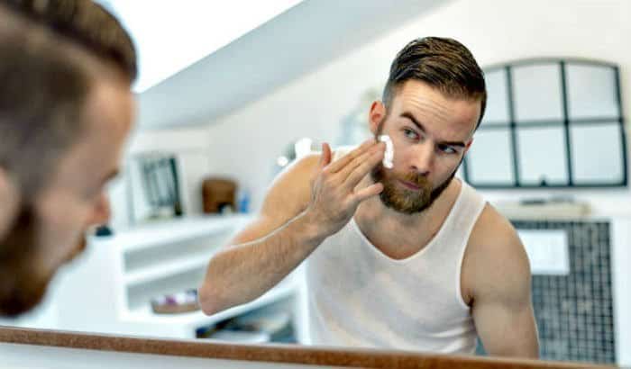 man using a beard moisturizer on his face