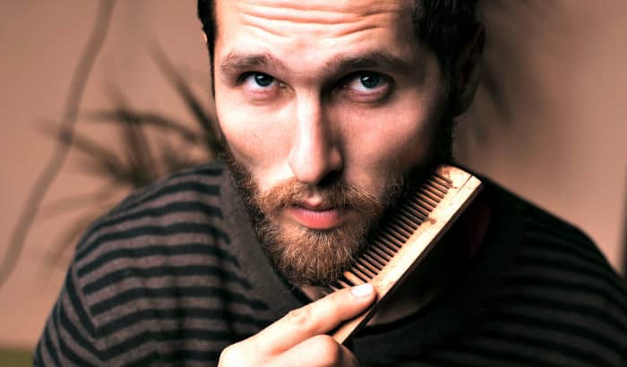 man using a big wooden beard comb