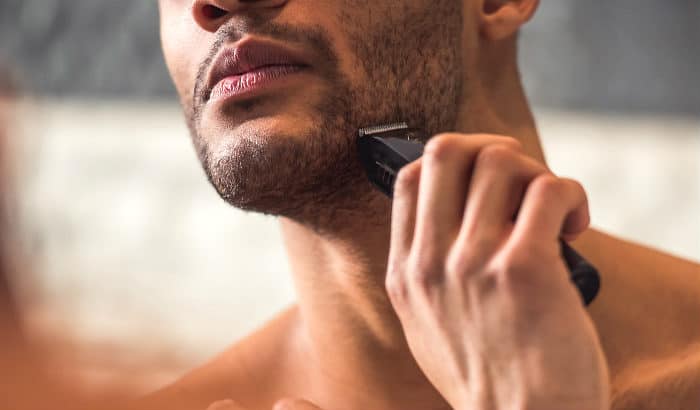 man using a stubble trimmer in front of a mirror