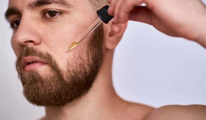 man using almond oil on his beard cheek