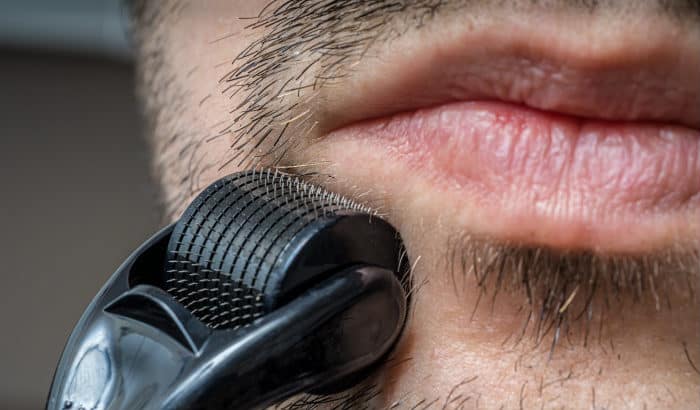 man using beard roller on mustache area