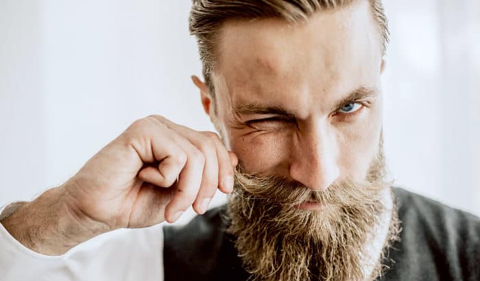 man using his fingers to apply mustache wax