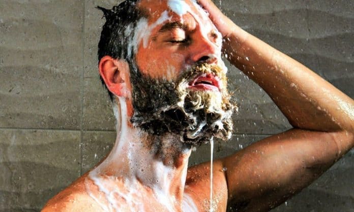 man washing his facial hair with shampoo