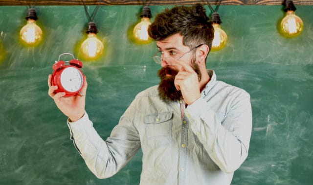 man with facial hair looking at a clock