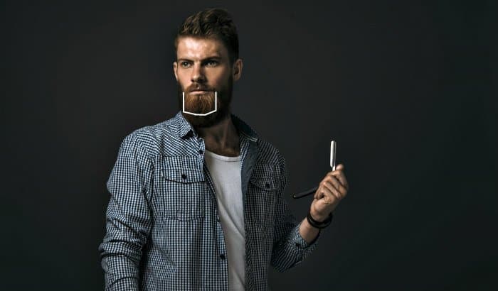 man with razor on his hand and goatee outline drawn on face