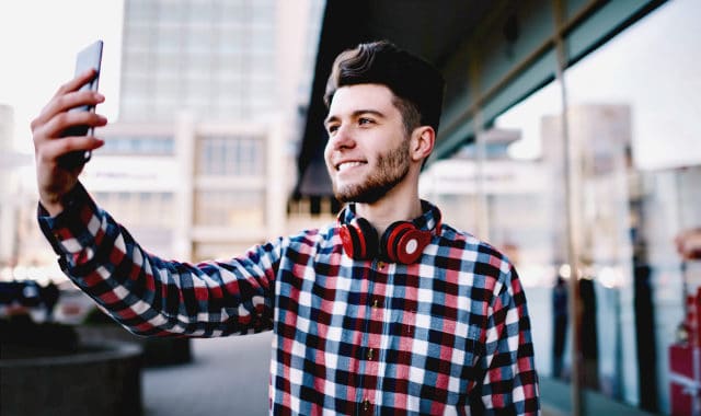 teen with facial hair taking a selfie